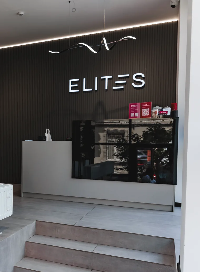 Рецепція клініки ELITES на вулиці Газовій у Львові: підсвічений знак на темній рифленій стіні